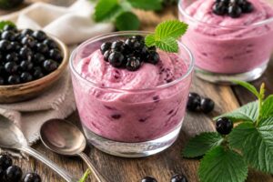 Schwarze Johannisbeer-Mousse ohne Gelatine in Portionsgläsern mit frischen Beeren und Minzeblättern