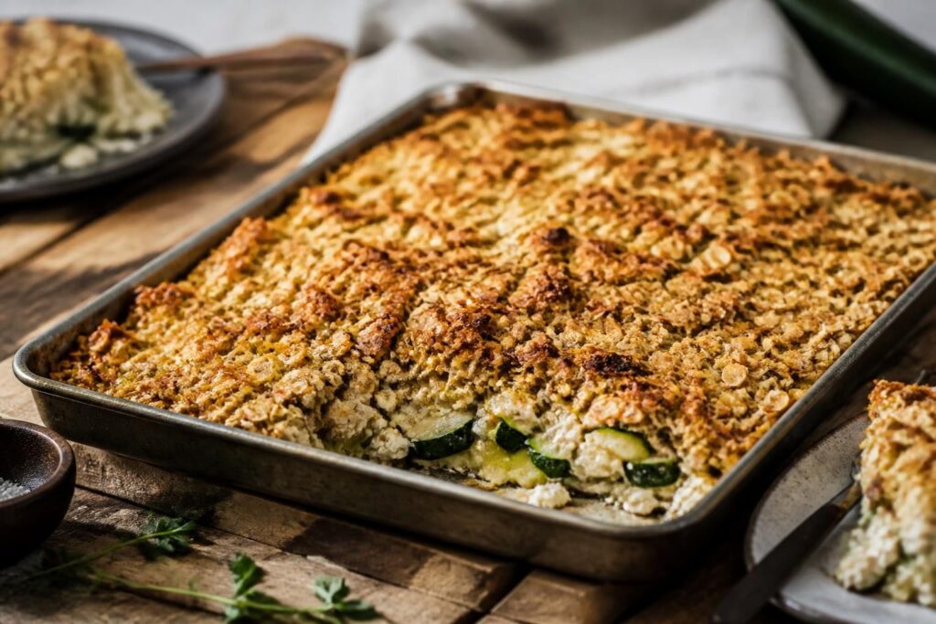 Zucchini-Feta-Auflauf vom Blech mit goldener Haferflocken-Kruste, frisch aus dem Ofen, von oben fotografiert