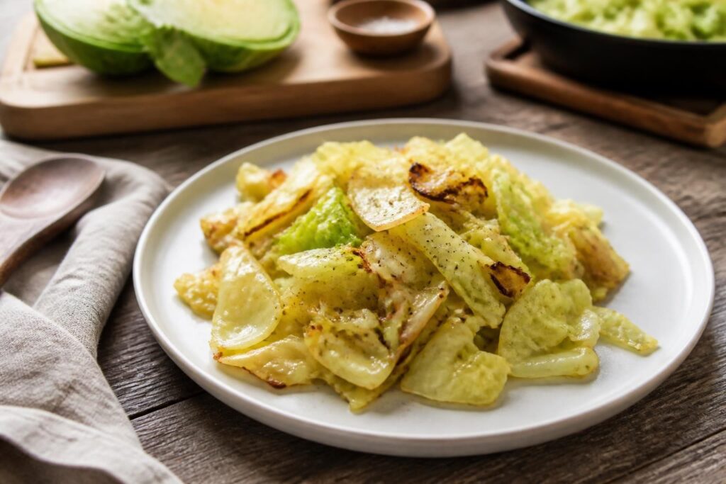 Spitzkohl-Rezept in der Pfanne mit Zwiebeln, Knoblauch und frischen Kräutern, serviert auf einem weißen Teller